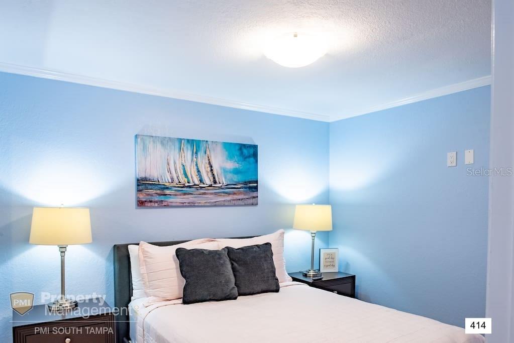 A bedroom features light blue walls, a sailboat painting, and two bedside lamps — 2506 N ROCKY POINT DRIVE UNIT 414, TAMPA, FL
