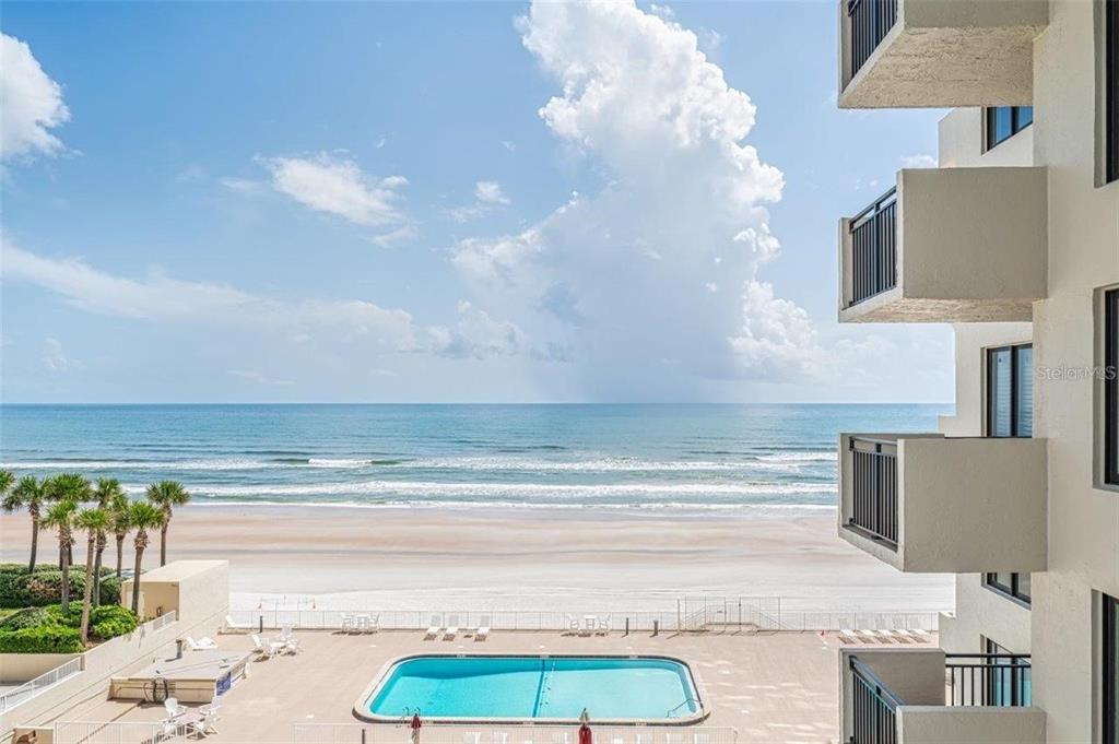 An elevated view of a beachside swimming pool and the ocean from a balcony — 2947 S ATLANTIC AVENUE UNIT 606, DAYTONA BEACH, FL