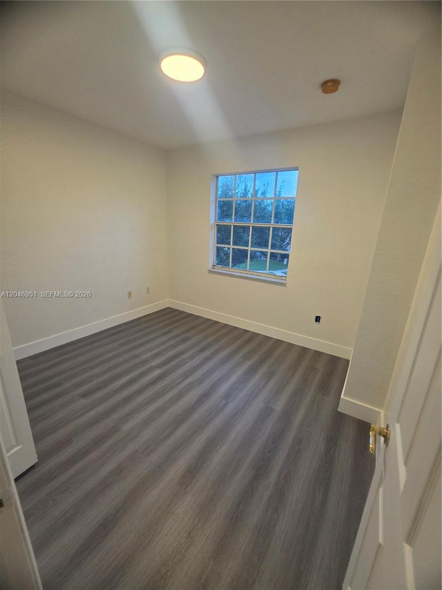 An empty bedroom features light-colored walls, a single window, and gray wood-look flooring — 2532 SW 85th Ter # 102, Miramar FL 33025, MIRAMAR, FL