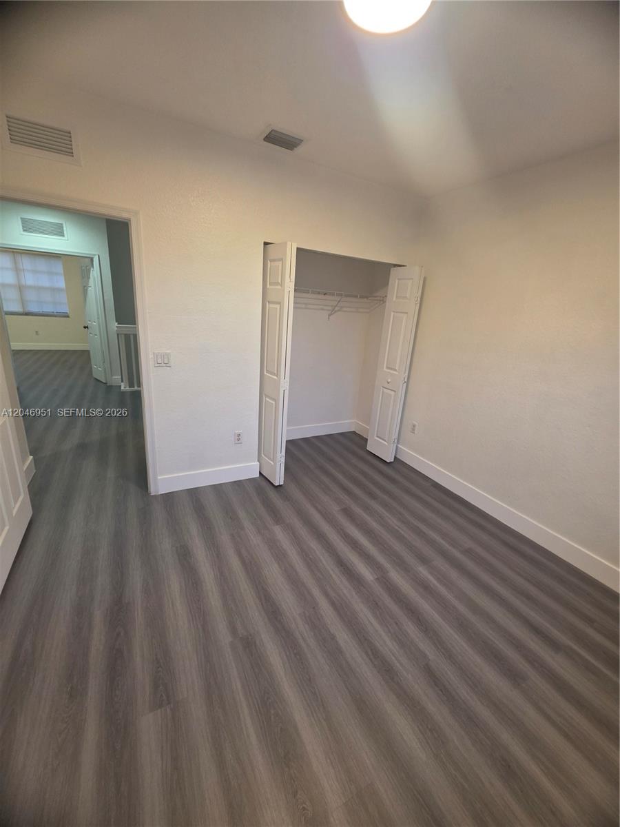 An empty bedroom features gray wood-look flooring, white walls, and an open closet — 2532 SW 85th Ter # 102, Miramar FL 33025, MIRAMAR, FL