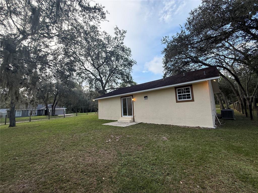 The exterior of a light-colored house features a sliding glass door and a small window — 40233 PALM STREET, LADY LAKE, FL