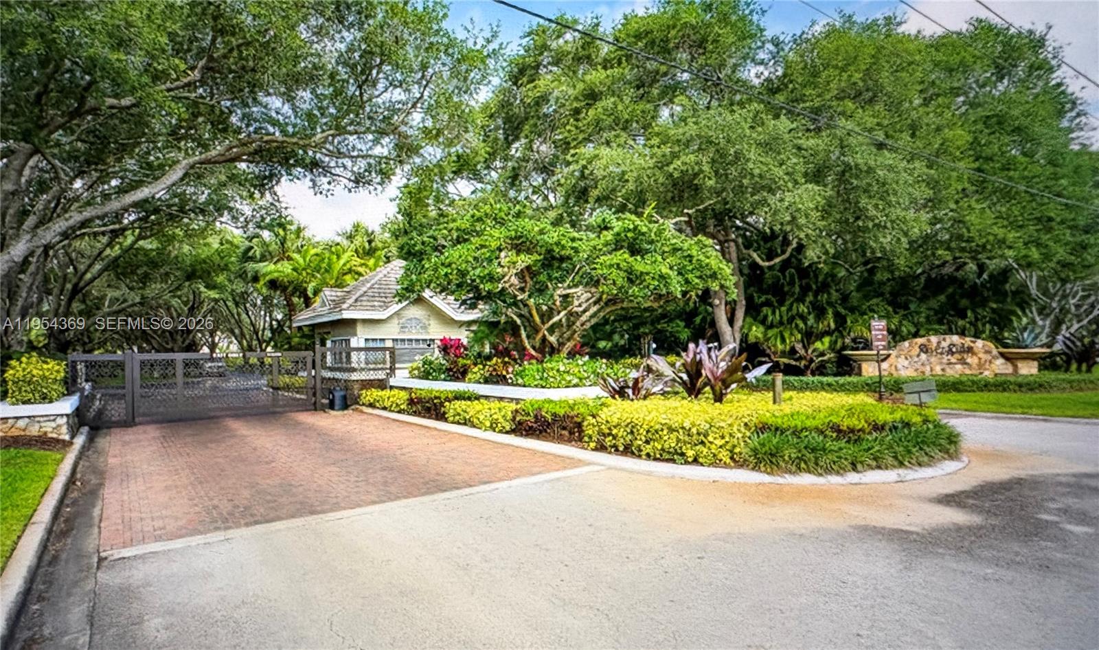 A gated entrance with a guardhouse, lush landscaping, and a stone community sign — 18265 SE Ridgeview Dr, Tequesta FL 33469, TEQUESTA, FL