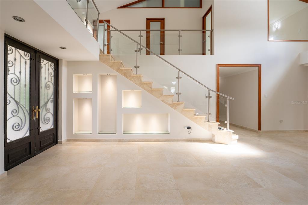 A foyer features a stone staircase with a glass railing and built-in illuminated wall niches — 254 SABANERA, DORADO, PR