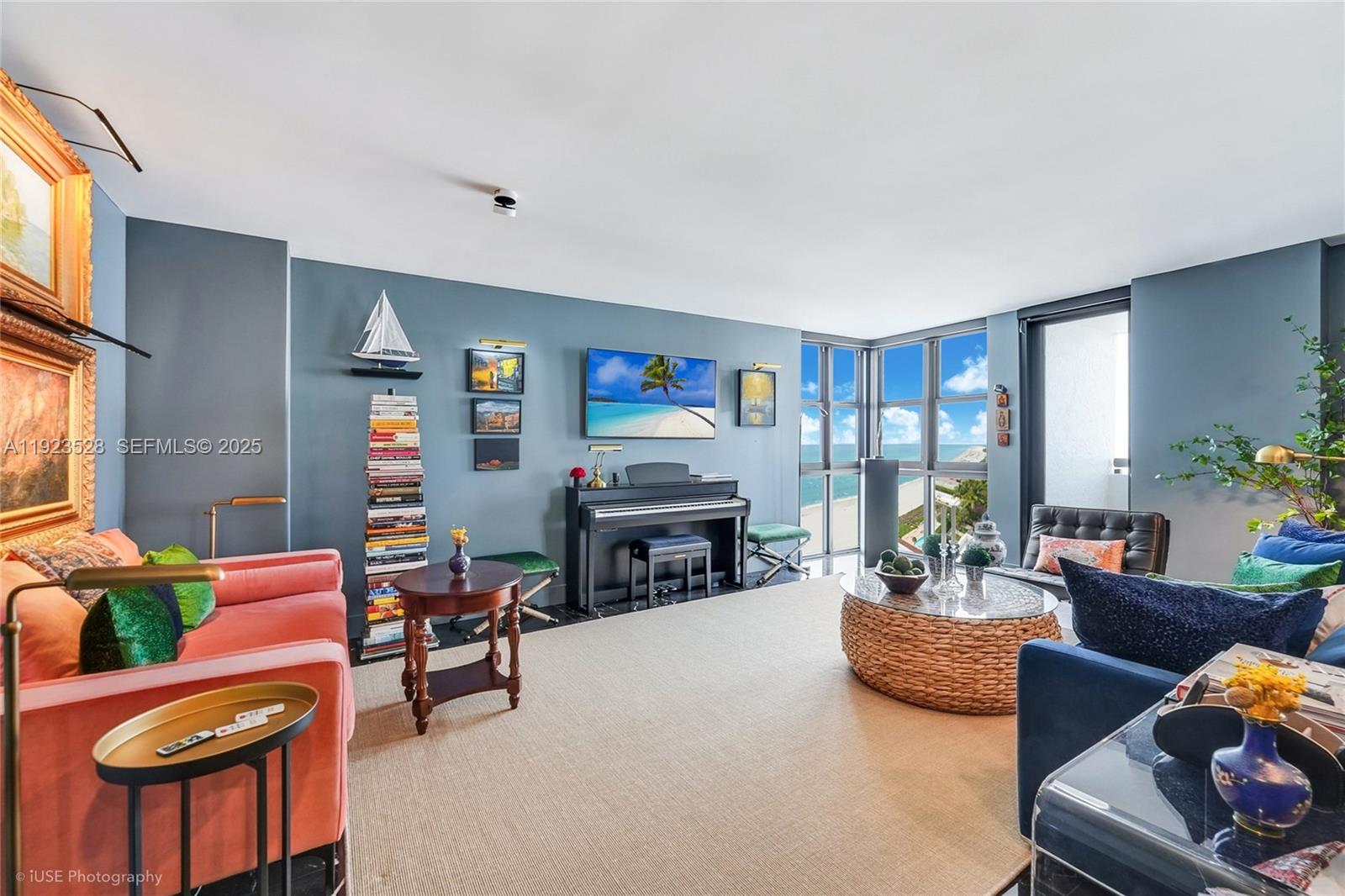 A living room features a piano, a coral sofa, blue walls, and floor-to-ceiling ocean views — 2555 Collins Ave, Miami Beach FL 33140, MIAMI BEACH, FL