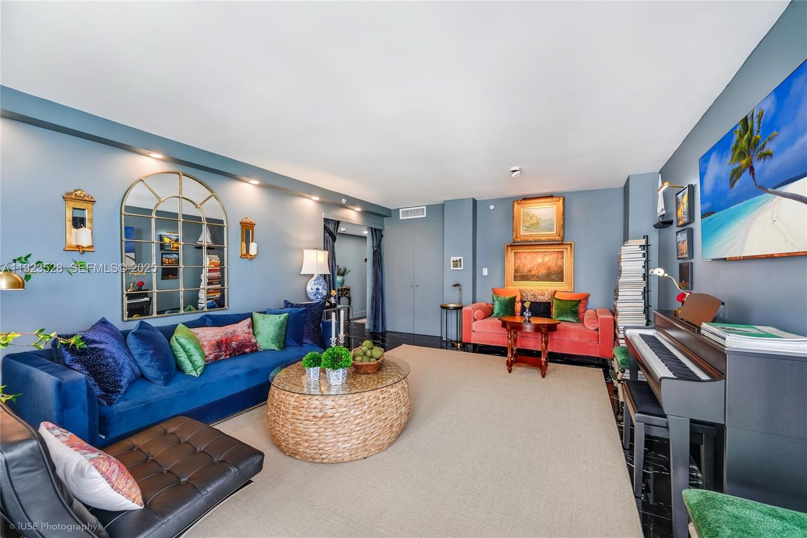 A living room features blue walls, a blue sofa, a coral sofa, and a piano — 2555 Collins Ave, Miami Beach FL 33140, MIAMI BEACH, FL