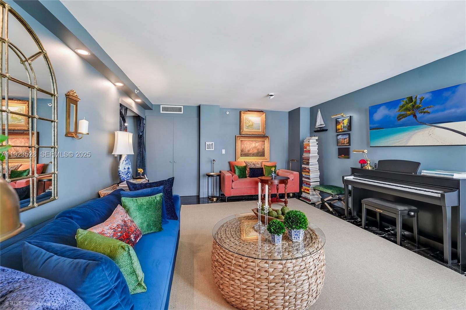 A living room features blue walls, a blue sofa, a piano, and a round wicker table — 2555 Collins Ave, Miami Beach FL 33140, MIAMI BEACH, FL