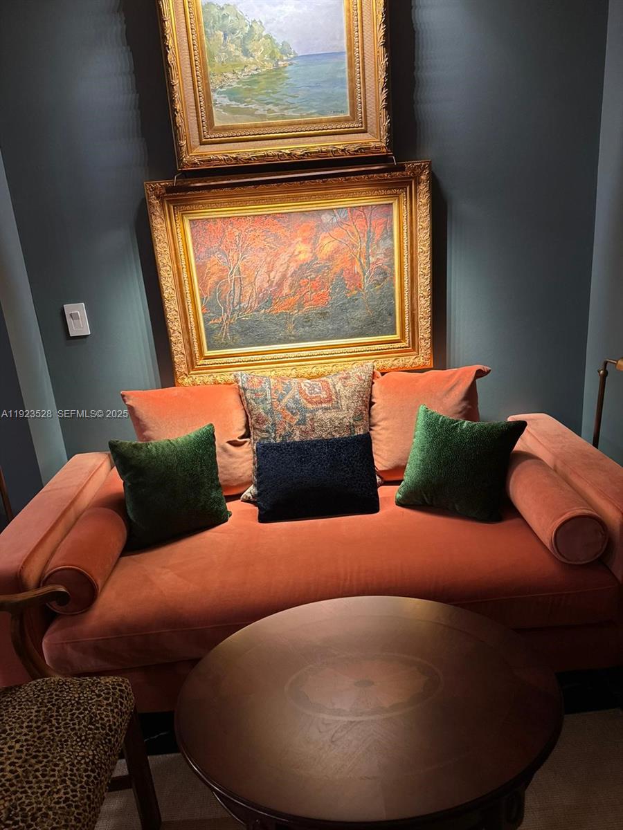 A velvet sofa with decorative pillows sits beneath two framed paintings on a dark wall — 2555 Collins Ave, Miami Beach FL 33140, MIAMI BEACH, FL