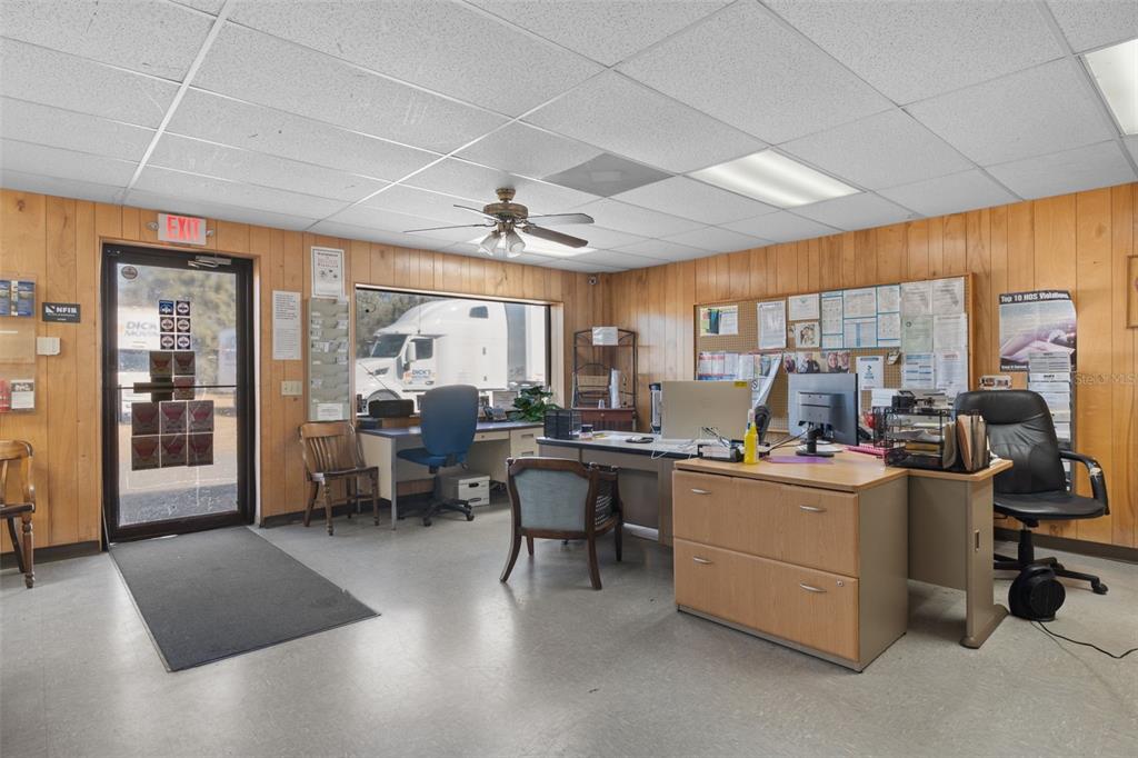 An office space features wood-paneled walls, a drop ceiling, and a view of a semi-truck — 6331 & 6275 S TEX POINT, HOMOSASSA, FL