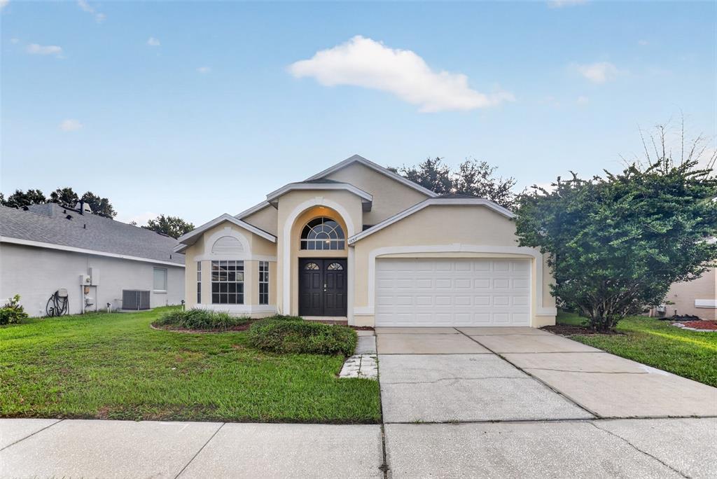 The exterior of a beige house features a double front door, arched window, and garage — 1157 BALLYSHANNON PARKWAY, ORLANDO, FL