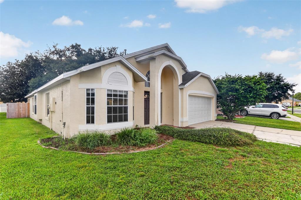 A single-story suburban house with a beige stucco exterior, arched entryway, and two-car garage — 1157 BALLYSHANNON PARKWAY, ORLANDO, FL