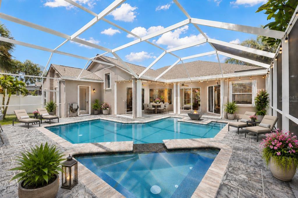 A backyard swimming pool and spa are enclosed by a screen cage behind a house — 695 SALT LAKE DRIVE, TARPON SPRINGS, FL