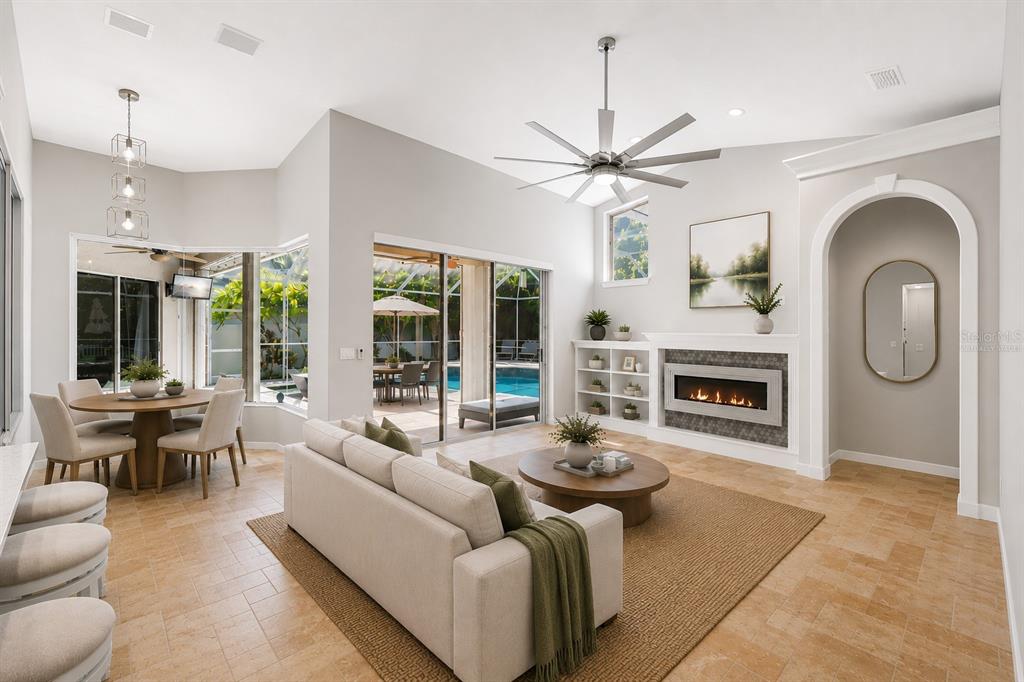 A bright living room with a fireplace, dining area, and sliding doors opening to a pool — 695 SALT LAKE DRIVE, TARPON SPRINGS, FL