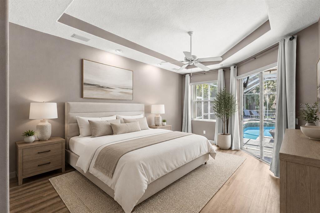 A bedroom with a king bed, tray ceiling, ceiling fan, and sliding doors to a pool — 695 SALT LAKE DRIVE, TARPON SPRINGS, FL