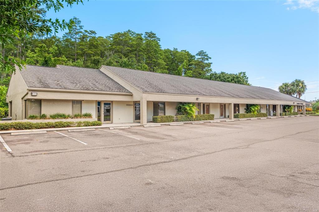 A single-story commercial office building with a parking lot and a wooded background — 2424 ENTERPRISE ROAD UNIT A, CLEARWATER, FL