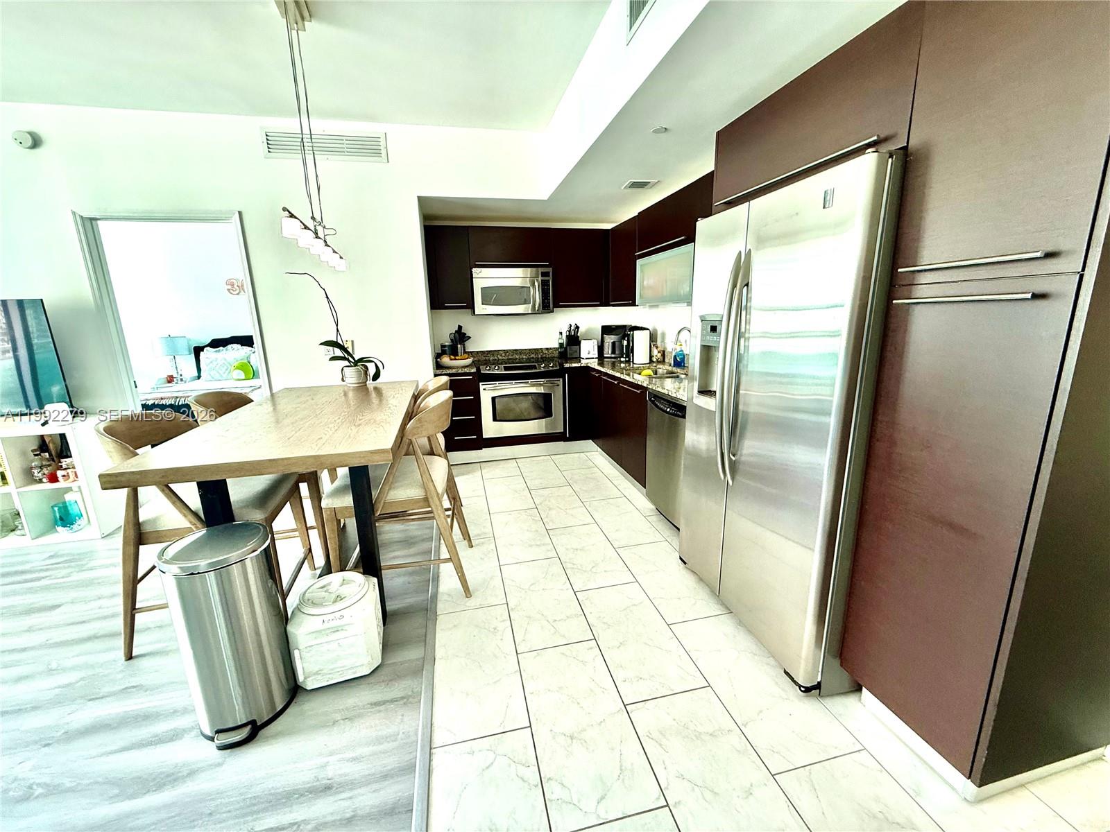 A kitchen features dark wood cabinets, stainless steel appliances, and light-colored tile flooring — 950 Brickell Bay Dr # 2706, Miami FL 33131, MIAMI, FL