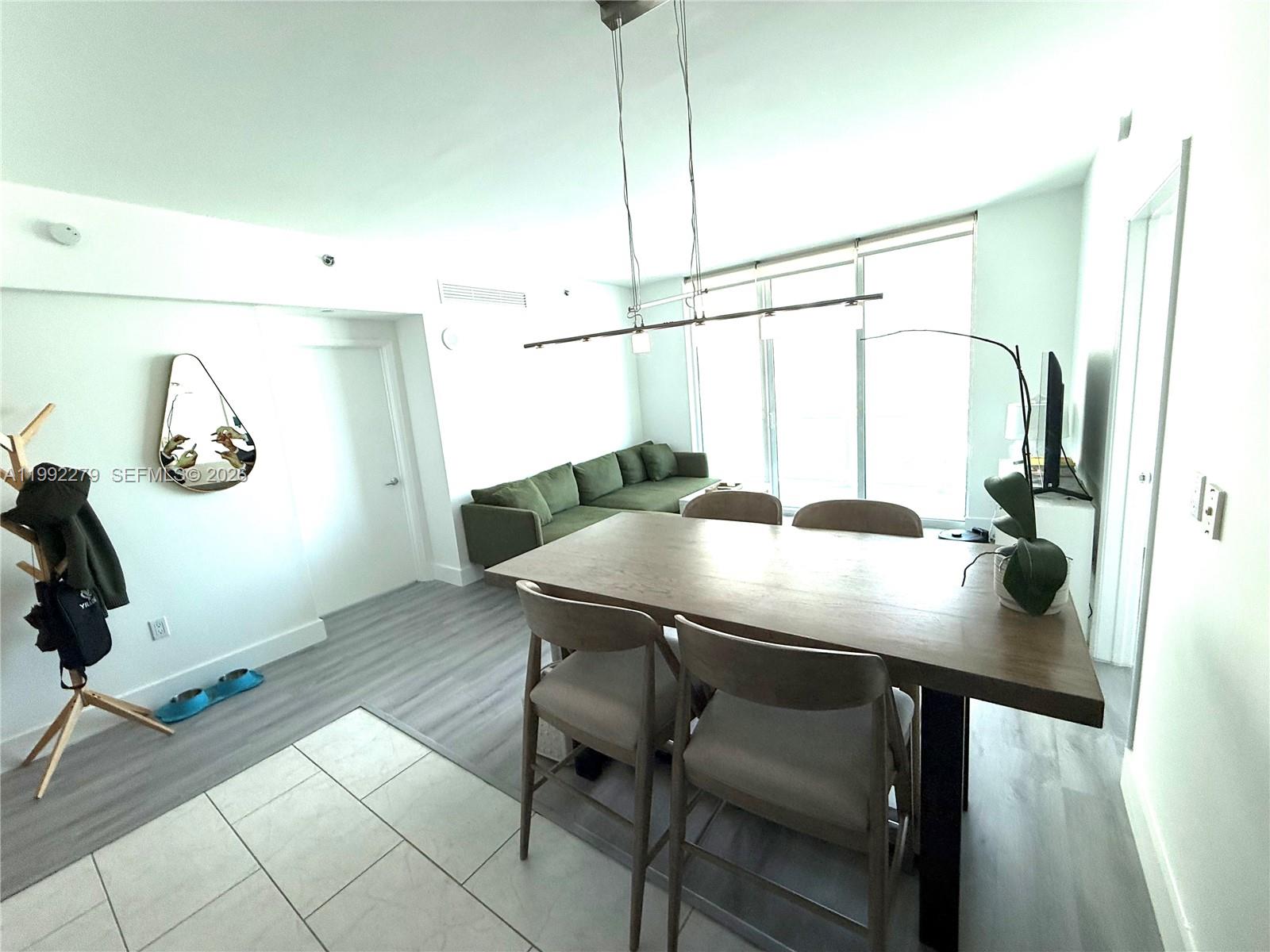 A dining area with a wooden table and chairs sits before a living room sofa — 950 Brickell Bay Dr # 2706, Miami FL 33131, MIAMI, FL