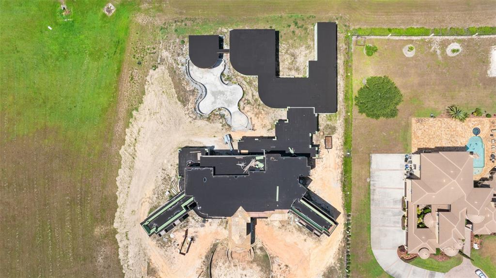 An aerial view shows a large house under construction with a pool and surrounding land — 9621 WINDY RIDGE ROAD, WINDERMERE, FL