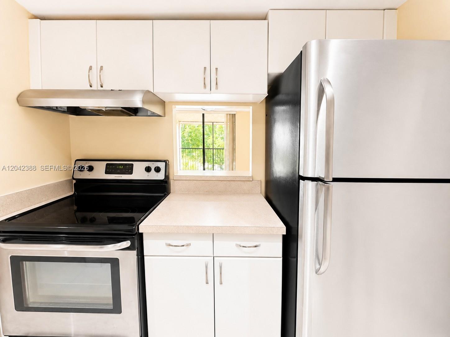 A kitchen features white cabinets, stainless steel appliances, and a small window looking outside — 14421 N Kendall Dr # 000, Miami FL 33186, MIAMI, FL