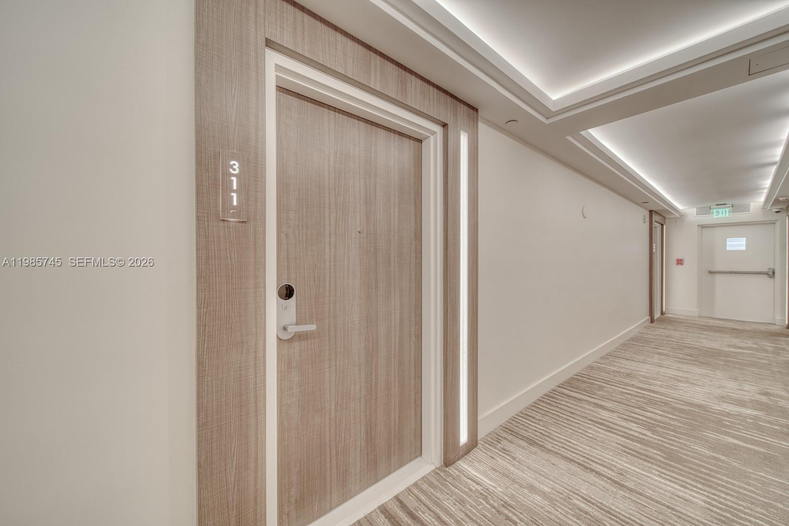 A wood-grain door labeled 311 sits in a modern hallway with recessed ceiling lighting — 2301 Collins Ave # 311, Miami Beach FL 33139, MIAMI BEACH, FL