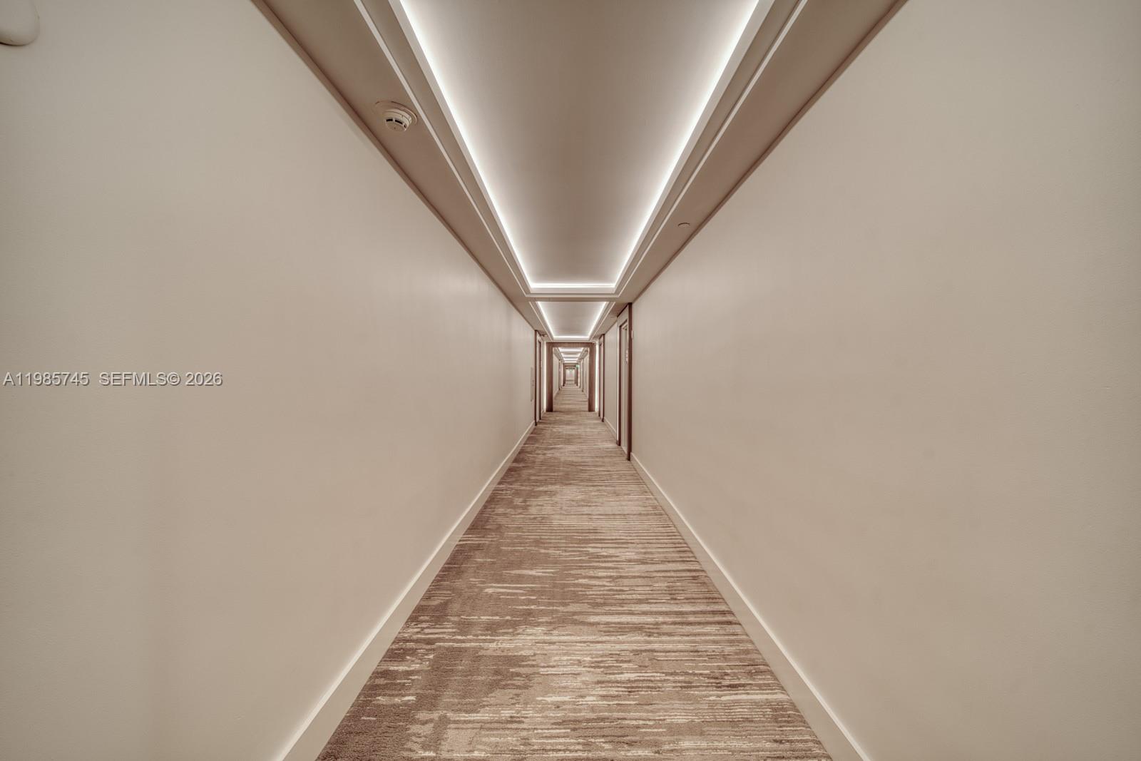 A long, narrow hotel-style hallway features recessed ceiling lighting and patterned carpeted flooring — 2301 Collins Ave # 311, Miami Beach FL 33139, MIAMI BEACH, FL