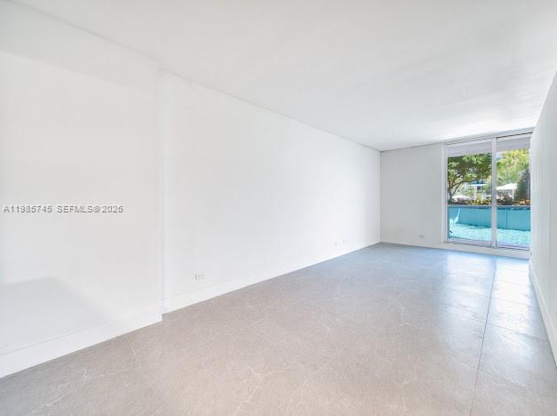 An empty room with white walls, light gray tile flooring, and a large sliding glass door — 2301 Collins Ave # 311, Miami Beach FL 33139, MIAMI BEACH, FL