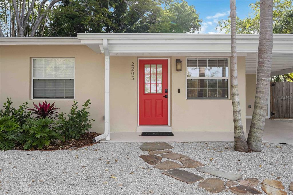 The exterior of a house features a bright red front door and a stone walkway — 2205 FLOYD STREET, SARASOTA, FL