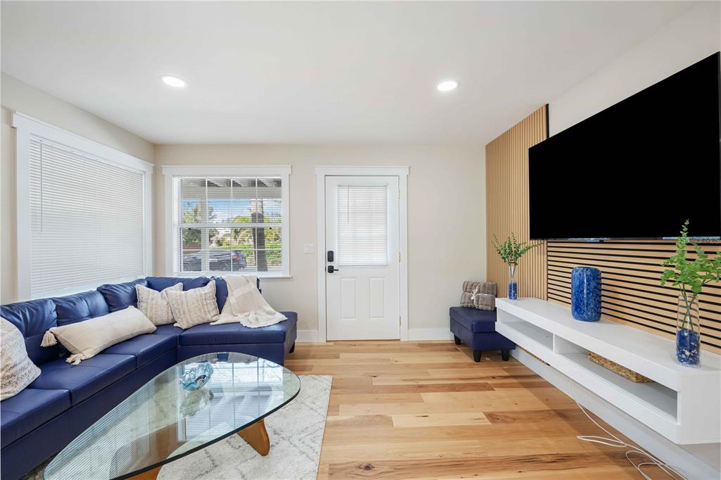 A living room features a blue sectional sofa, wood-slat wall paneling, and a white media console — 2205 FLOYD STREET, SARASOTA, FL
