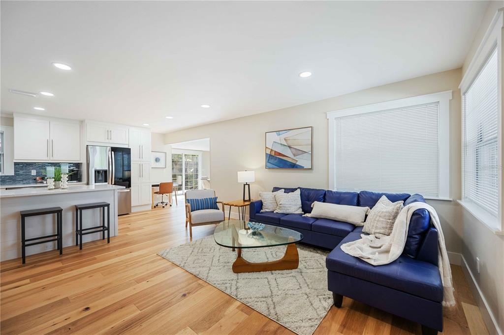 A bright open-concept living room features a blue sectional sofa, glass coffee table, and kitchen — 2205 FLOYD STREET, SARASOTA, FL