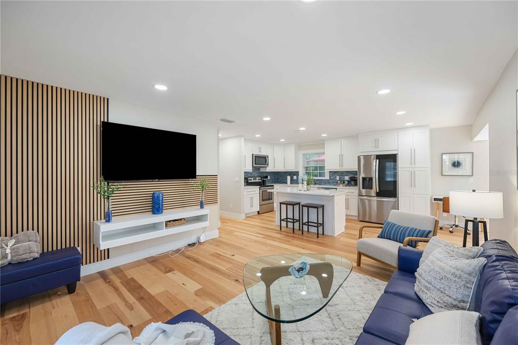 An open-concept living room and kitchen featuring wood flooring, a slatted accent wall, and cabinetry — 2205 FLOYD STREET, SARASOTA, FL