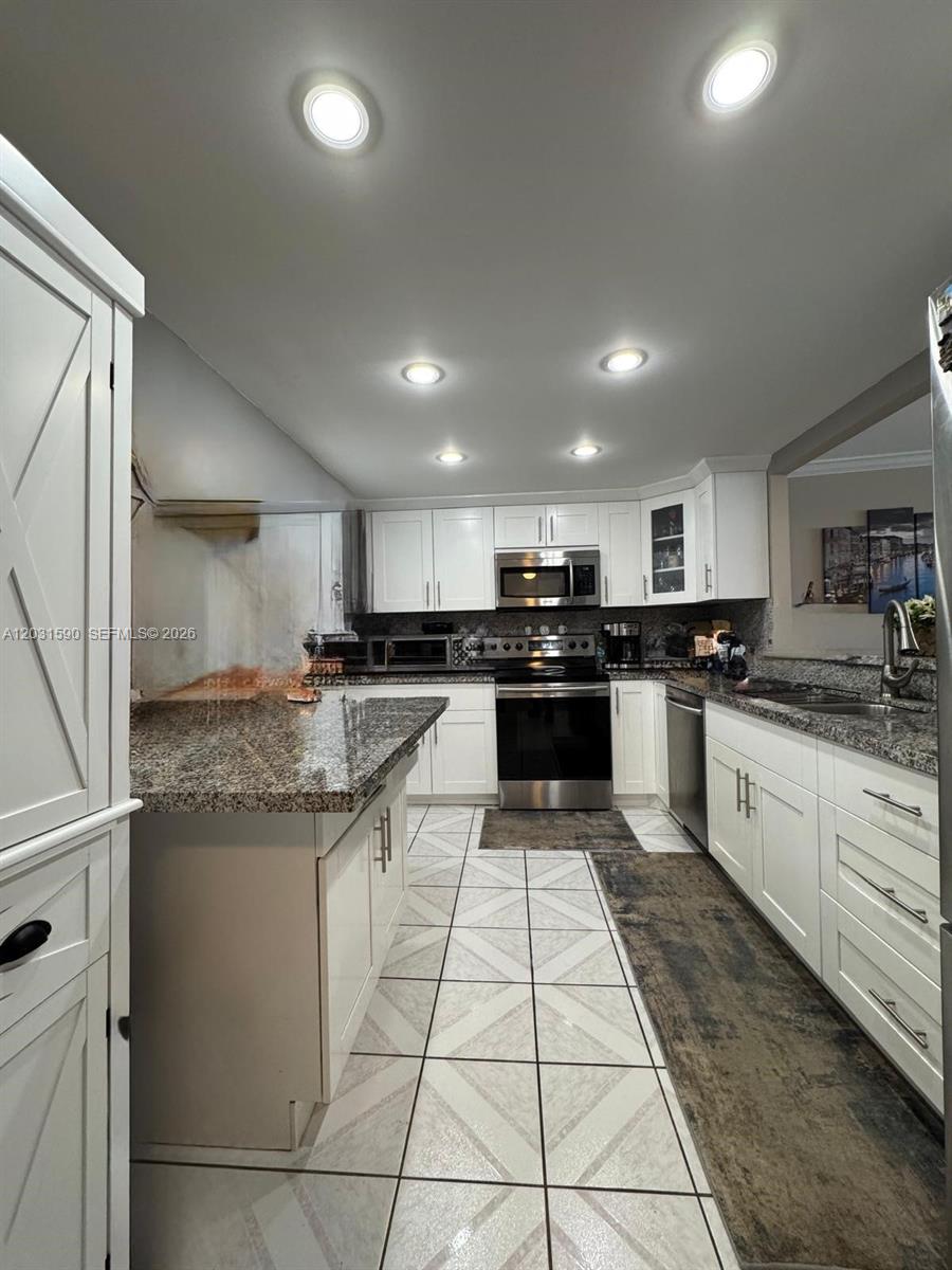 A kitchen features white cabinetry, granite countertops, stainless steel appliances, and tiled flooring — 3800 S Ocean Dr, Hollywood FL 33019, HOLLYWOOD, FL