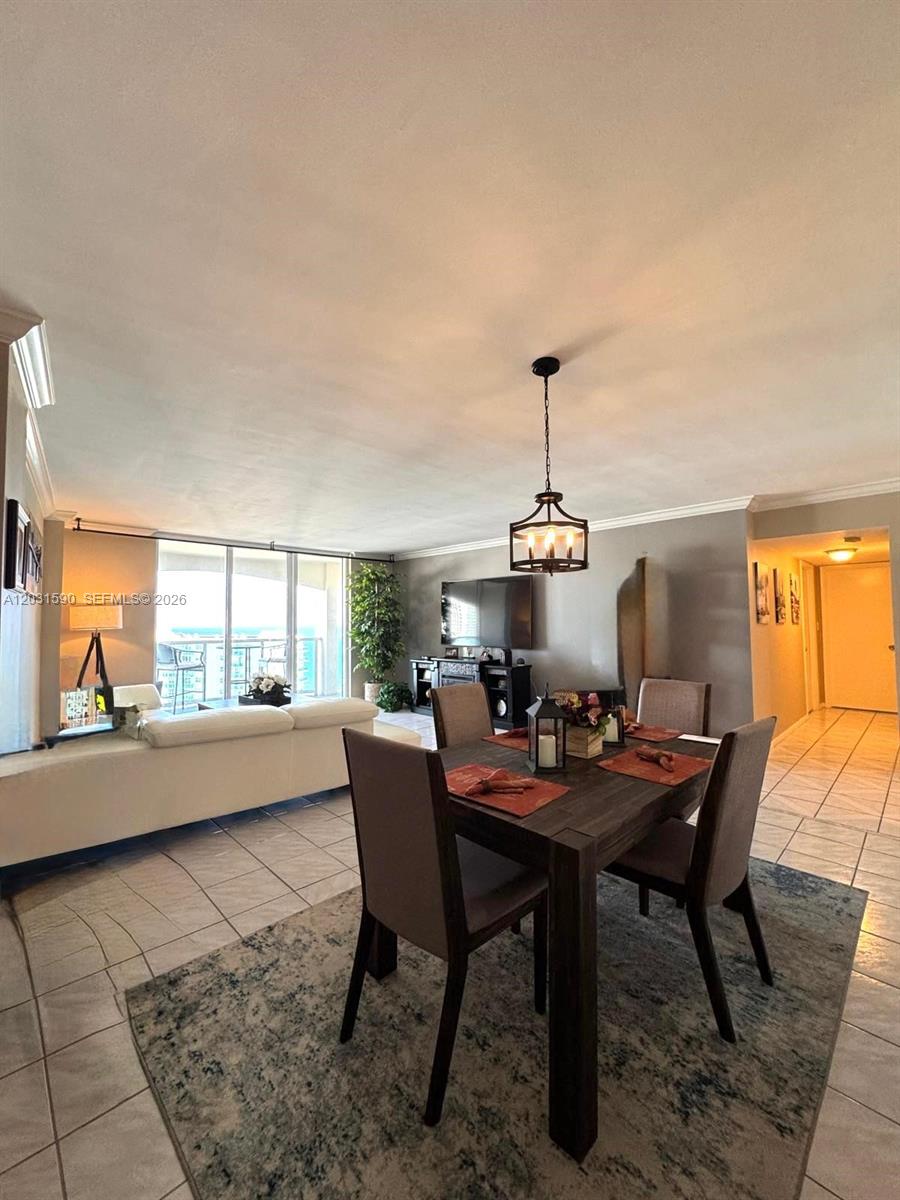 An open-concept living and dining area features tile flooring, a dark wood table, and balcony views — 3800 S Ocean Dr, Hollywood FL 33019, HOLLYWOOD, FL