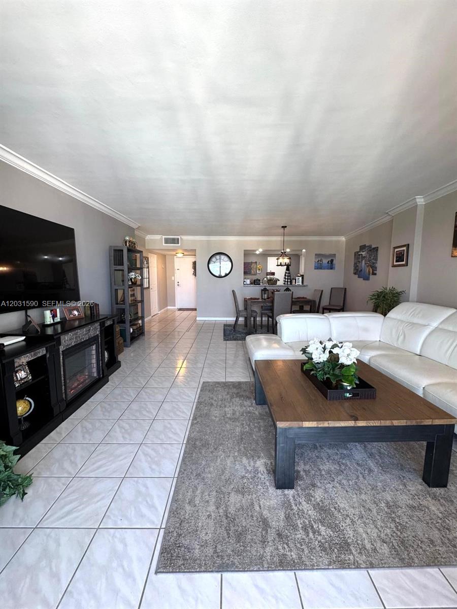 A living room features white tile floors, a white sectional sofa, and a fireplace console — 3800 S Ocean Dr, Hollywood FL 33019, HOLLYWOOD, FL