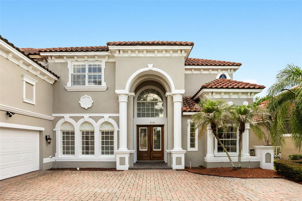A two-story house with a stucco exterior, arched entryway, and a brick paver driveway — 2724 NORTHAMPTON AVENUE, ORLANDO, FL
