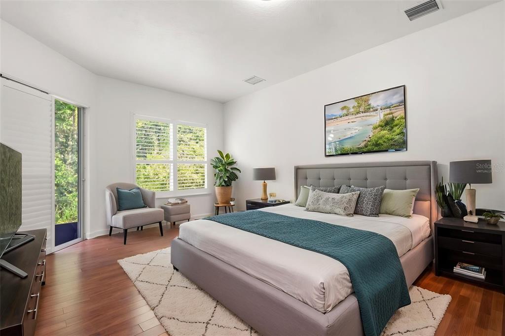 A bedroom features a gray upholstered bed, wood flooring, a white rug, and a sliding door — 2724 NORTHAMPTON AVENUE, ORLANDO, FL