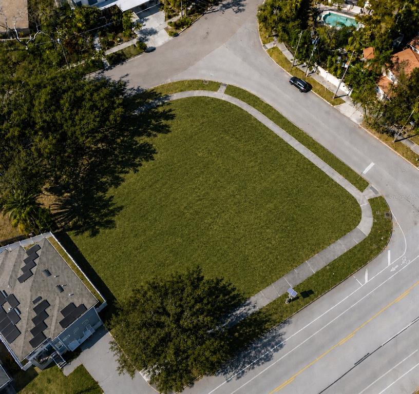 An aerial view shows a vacant corner lot covered in grass next to a road — 116 W DAVIS BOULEVARD, TAMPA, FL