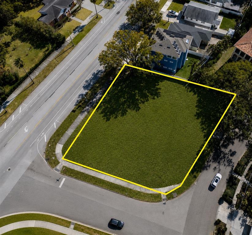 An aerial view shows a vacant, grass-covered corner lot outlined in yellow — 116 W DAVIS BOULEVARD, TAMPA, FL