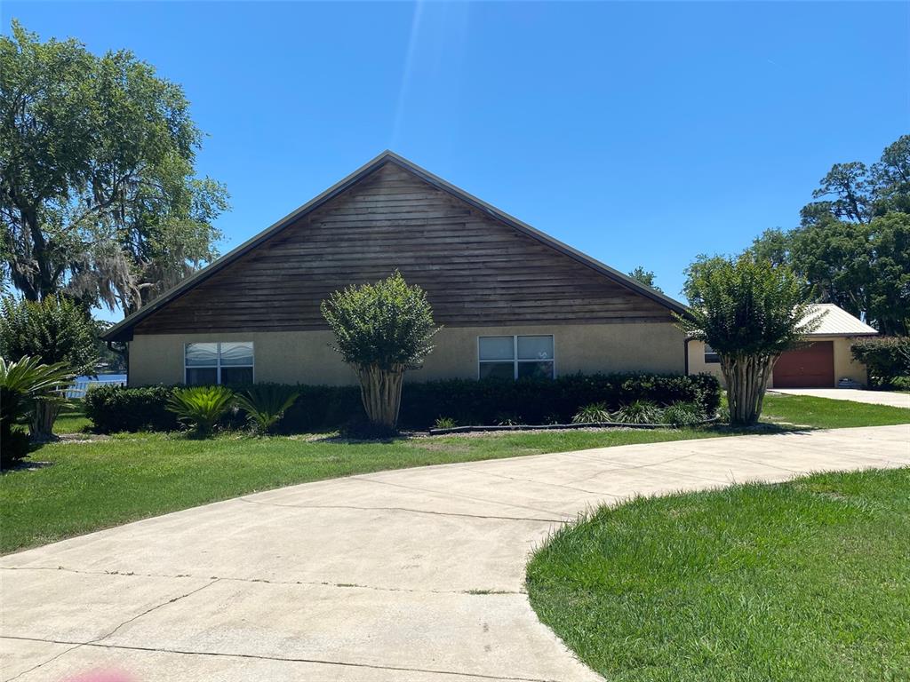 A single-story house with a wood-sided gable, stucco walls, and a curved concrete driveway — 229 LAKE IDA POINT DRIVE, INTERLACHEN, FL