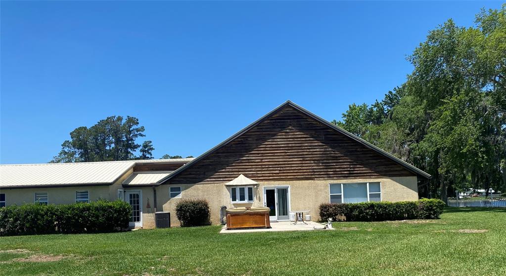 The exterior of a house features a large gable roof, wood siding, and a patio — 229 LAKE IDA POINT DRIVE, INTERLACHEN, FL