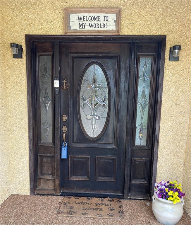 A dark wood front door with glass inserts and sidelights sits under a welcome sign — 229 LAKE IDA POINT DRIVE, INTERLACHEN, FL
