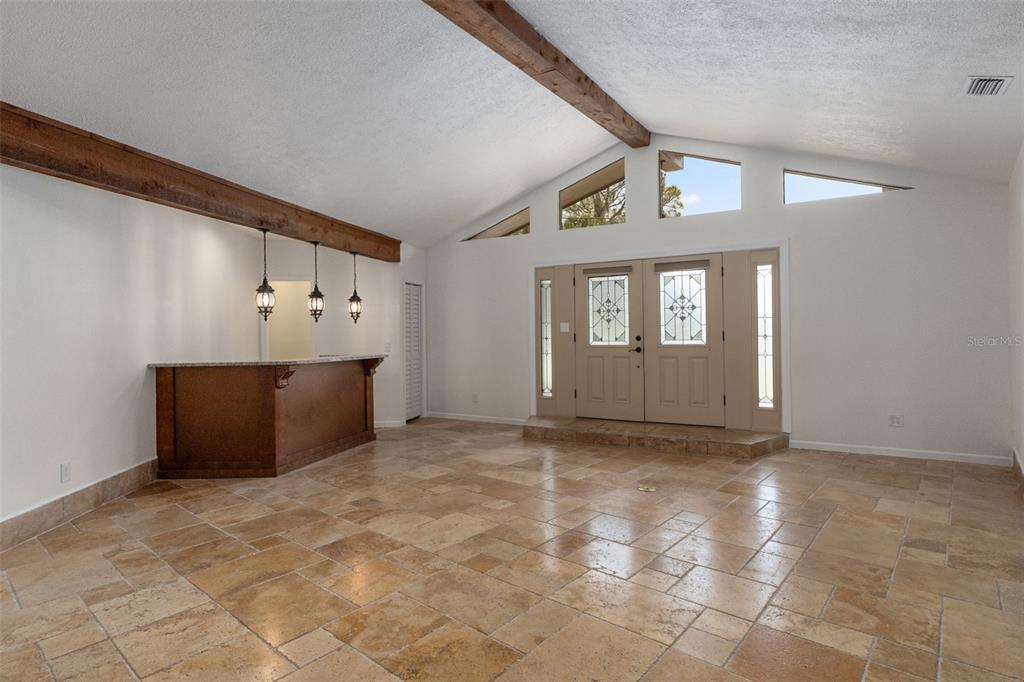 A spacious room features a built-in bar, vaulted ceilings with exposed beams, and tiled flooring — 239 SE PARADISE POINT ROAD, CRYSTAL RIVER, FL