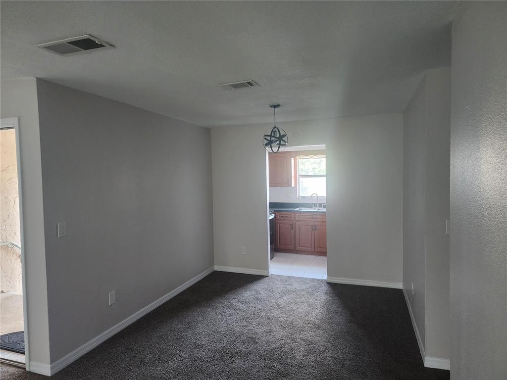 A carpeted dining area leads into a kitchen with wooden cabinets and a window — 7210 N MANHATTAN AVENUE UNIT 1821, TAMPA, FL