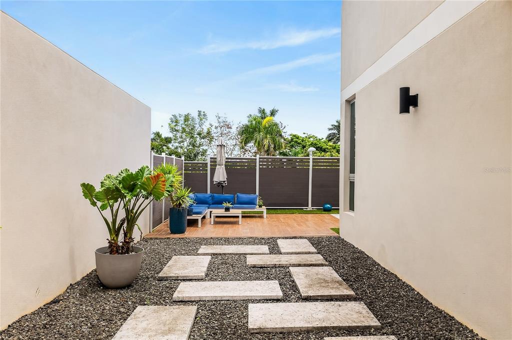 A modern outdoor patio features stone pavers, a gravel ground, and a blue seating area — 110 CENTRAL PARK, RIVIERA VILLAGE, BAYAMON, PR