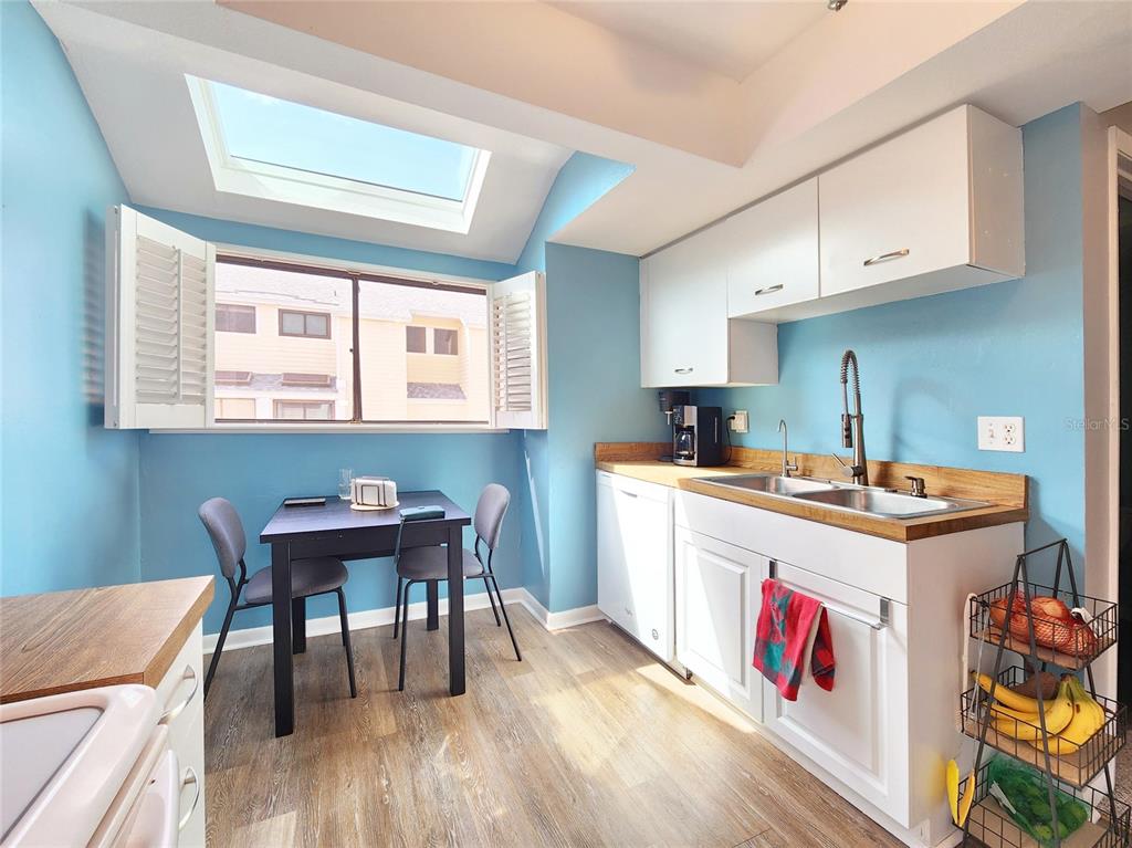 A kitchen with blue walls, white cabinets, a wood countertop, and a skylight above — 1500 SUNSET RD BLDG C UNIT C7, TARPON SPRINGS, FL