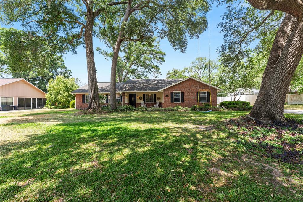 A single-story brick house with a front yard, large trees, and a hanging rope swing — 986 SE 57TH AVENUE, OCALA, FL
