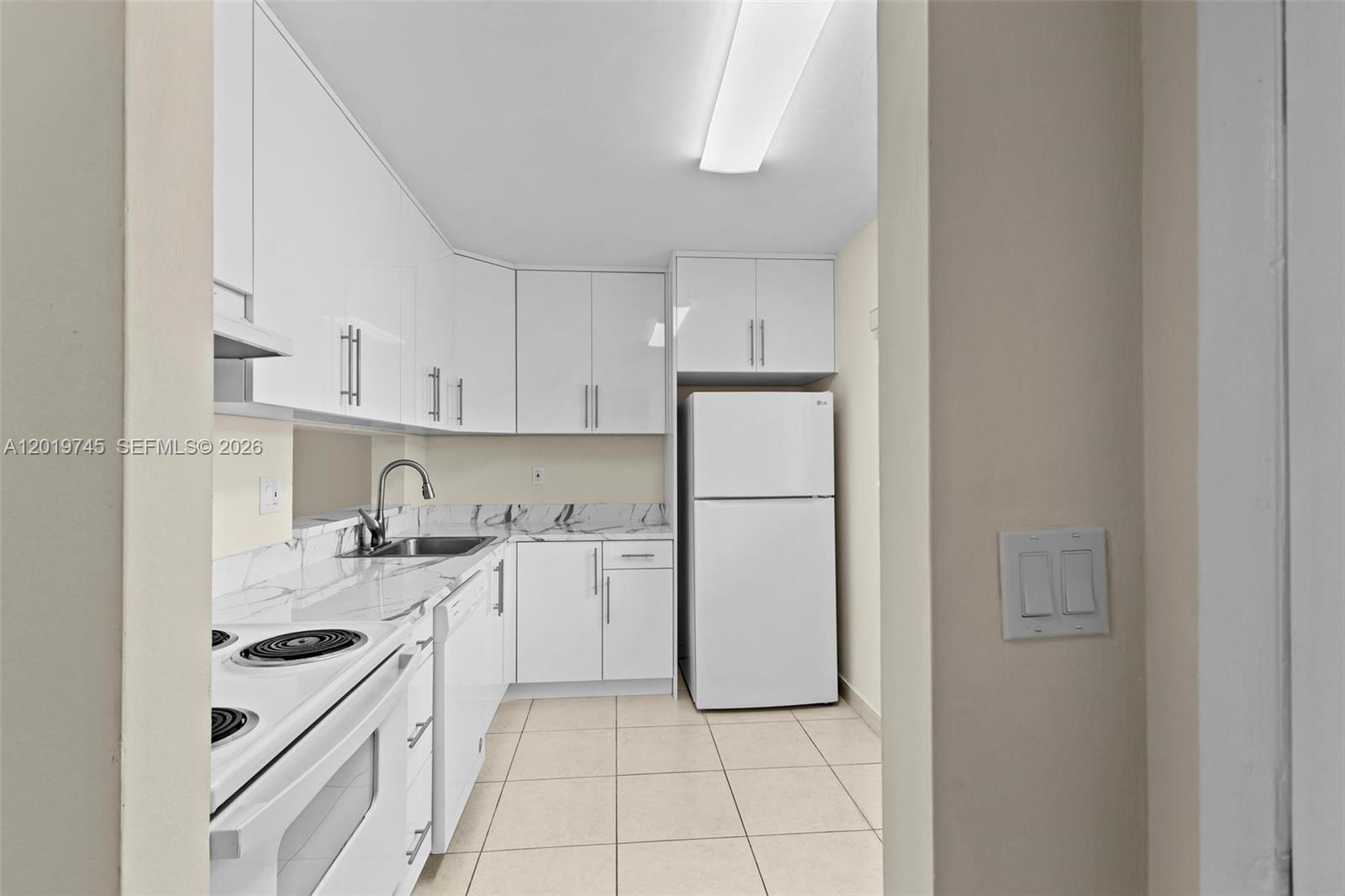 A kitchen features white cabinets, a white refrigerator, and a marble-patterned countertop — 8600 SW 133rd Ave Rd # 410, Miami FL 33183, MIAMI, FL