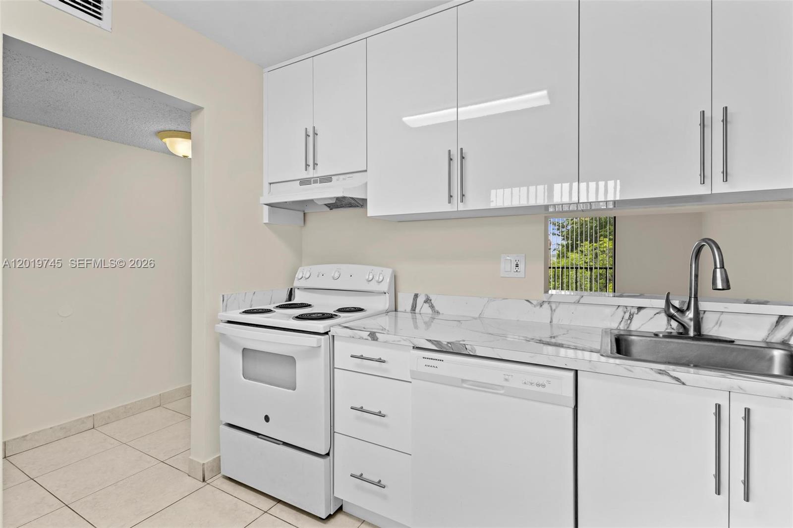 A kitchen features white cabinets, a white stove, a dishwasher, and marble-patterned countertops — 8600 SW 133rd Ave Rd # 410, Miami FL 33183, MIAMI, FL