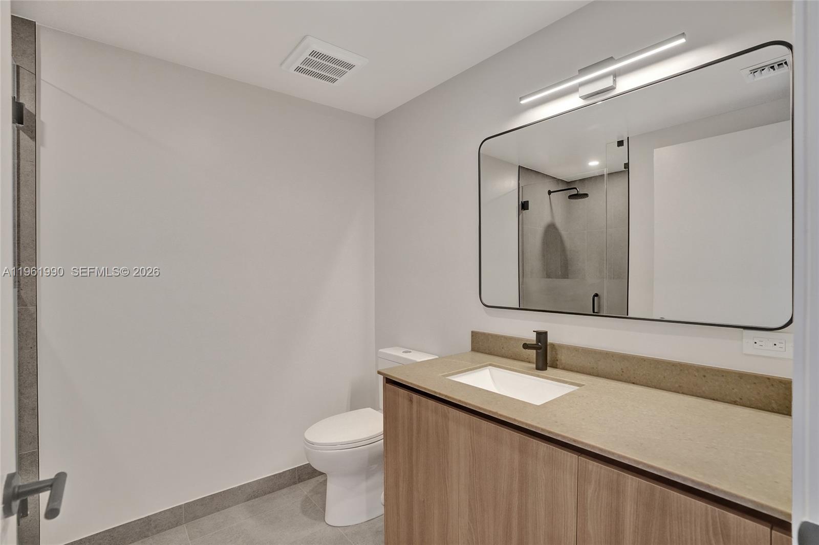 A modern bathroom features a wood vanity, a rectangular mirror, and a glass-enclosed shower — 121 NE 5th Street # 401B, Miami FL 33132, MIAMI, FL