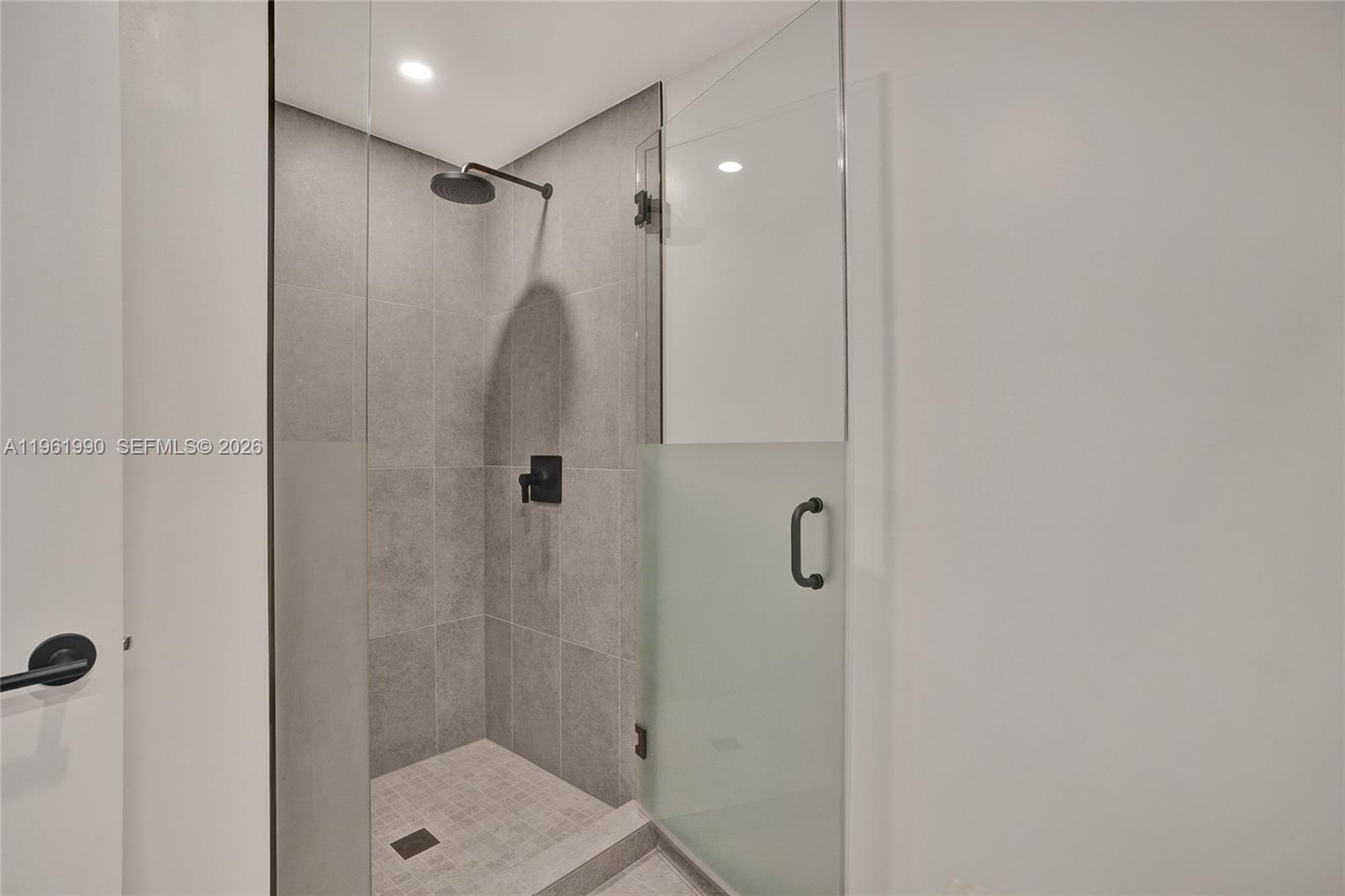 A walk-in shower features gray tiled walls, a black shower head, and a glass door — 121 NE 5th Street # 401B, Miami FL 33132, MIAMI, FL