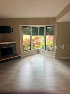 A living room features light wood-look flooring, a stone fireplace, and a large bay window — 485 WESTLAKE BOULEVARD UNIT 70, PALM HARBOR, FL