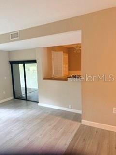 A living room with light wood-look flooring leads to a kitchen pass-through and sliding glass doors — 485 WESTLAKE BOULEVARD UNIT 70, PALM HARBOR, FL